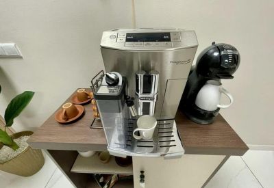 Coffee station with an espresso machine and a pod brewer on a wooden cabinet.