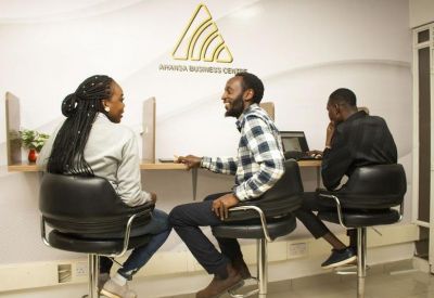 Coworking space with black leather stools and people working at a counter.
