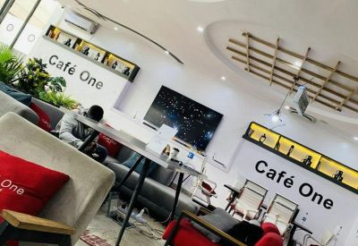Spacious communal lounge at Café One, 28 Okpara Avenue, Enugu, Nigeria with modern seating and decorative wood ceilings.