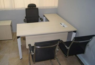 Private L-shaped desk workstation with black ergonomic chairs and neutral walls.
