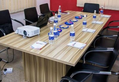 Professional meeting room with a wooden table, projector, and bottled water service.