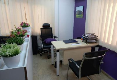 Compact office suite featuring a desk, purple accent wall, and potted greenery.