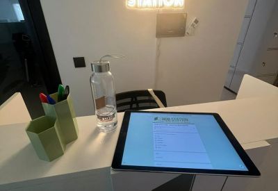 Reception counter featuring a check-in tablet and a glowing neon Hub Station sign on the wall.