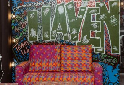 Colorful lounge area with a patterned sofa and a graffiti-style wall featuring The Haven text.