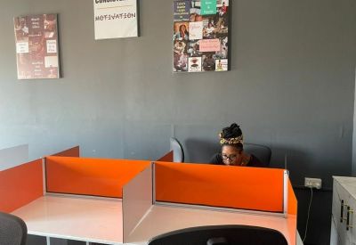 Workspace with white desks, orange privacy dividers, and motivational posters on a grey wall.