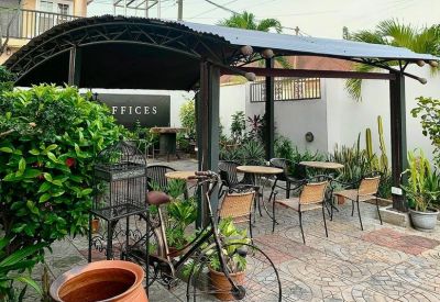 Outdoor covered seating area with wooden tables and a bicycle planter.