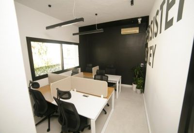 Workspace with white desks, black ergonomic chairs, and a black accent wall.