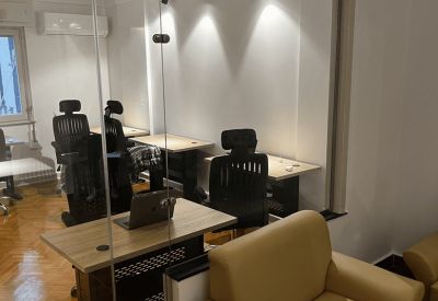 Meeting room seen through glass doors with a wooden desk, laptop, and comfortable tan armchair.