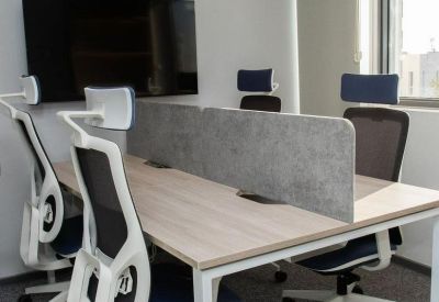 Shared workspace with four ergonomic white chairs and a central privacy screen.