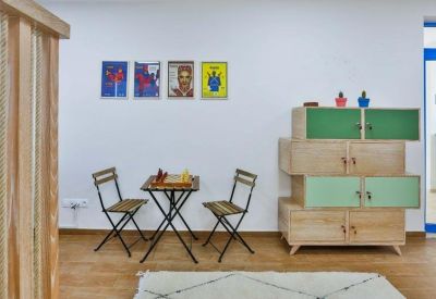 Bright breakout corner with a wooden chess table, folding chairs, and colorful wall art.