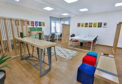 Spacious open-plan coworking area with high-top tables, white desks, and wooden privacy screens.