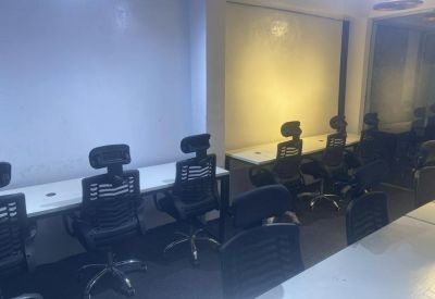 Open-plan office area with several black workstations and white desks.
