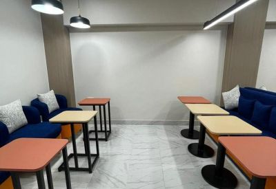 Bright breakout space featuring modern blue armchairs and small cafe tables.