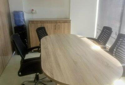 Meeting room with a light wood oval table and black mesh chairs.