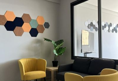 Bright lounge featuring yellow armchairs and geometric wall decor.
