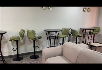 Lounge area featuring high-top bistro tables and stylish green bar stools against a neutral wall.