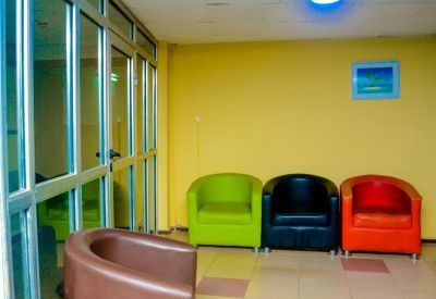 Reception waiting area with colorful modern tub chairs and a glass partition wall.