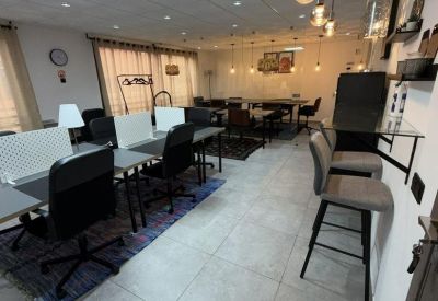 Meeting area with high stools, glass tables, and contemporary hanging light fixtures.