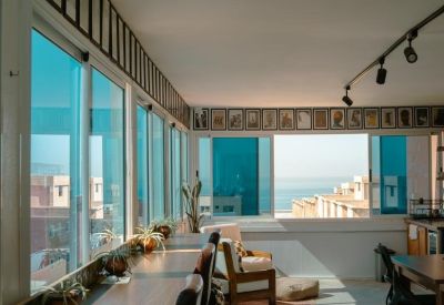 Sun-drenched bar seating overlooking a coastal view with potted plants.