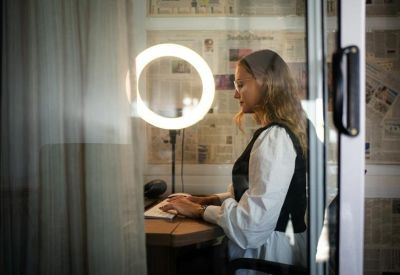 Close-up of a person typing at a standing desk behind a glass wall.