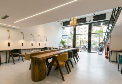 Bright workspace featuring large windows, a metal staircase, and contemporary lighting.