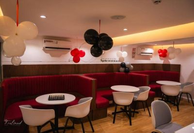 Breakout area with red velvet booths and round white tables.