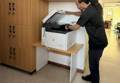 Employee using a printer beside wooden cabinets.