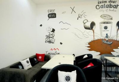 Communal lounge area featuring a sofa with cushions and wall art depicting coffee and local themes.
