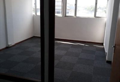 Bright private office featuring grey carpet tiles and large windows.