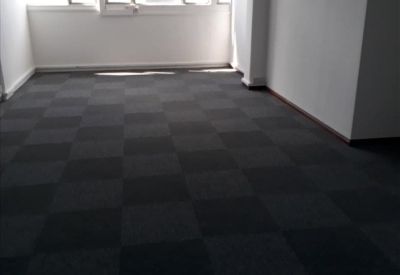 Empty office suite with checkerboard carpeting and natural light.