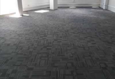 Spacious open-plan office area with patterned grey carpet and white pillars.