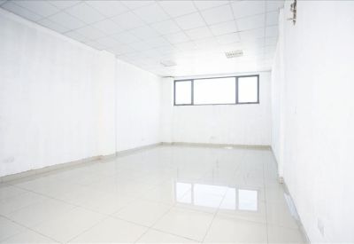 Empty white office suite with polished tiled floors and a large window providing natural light.