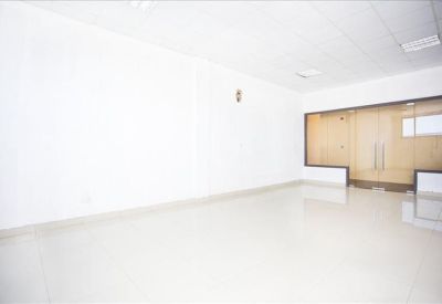 Brightly lit open-plan workspace featuring a glass-enclosed partitioned area and reflective flooring.