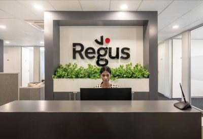 Reception desk with Regus branding and a green plant wall.
