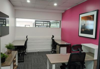 Private four-person office suite with a vibrant pink feature wall.
