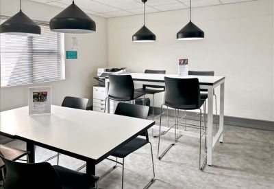 Communal break area with high-top tables, bar stools, and modern pendant lighting.