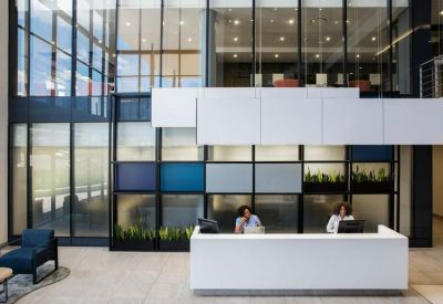 Bright, high-ceilinged reception area with white front desk and geometric wall art.