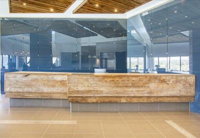 Long reception desk with a natural wood finish set against a sleek dark reflective backdrop.