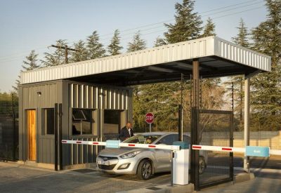 Security entrance gatehouse with a silver car passing through a boom barrier.