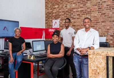 A team of four colleagues in a creative office with an exposed brick wall.