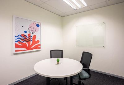Small meeting room with a round white table and abstract coral wall art.