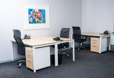 Modern three-person office suite with light wood desks and ergonomic mesh chairs.