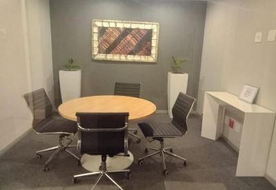 Small meeting room with a round wooden table and grey executive chairs.