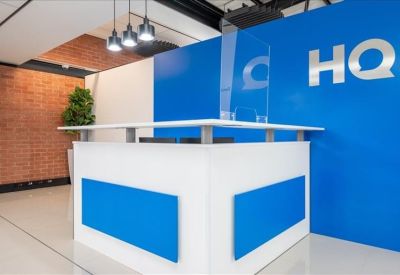 Reception area featuring a white desk, blue accent panels, and a branded logo wall.
