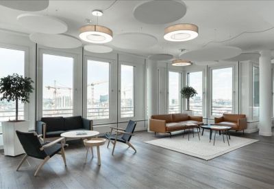 Modern breakout space with black and leather seating arrangements and large windows.