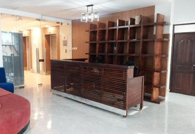 Wooden reception desk with a matching geometric bookshelf and red curved sofa.
