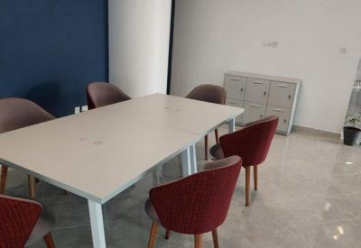 Meeting room with a white rectangular table, red velvet chairs, and a dark blue accent wall.