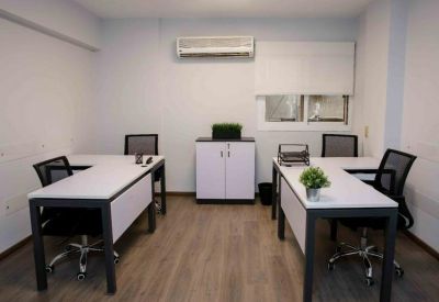 Bright office space featuring two L-shaped desks and an air conditioning unit.