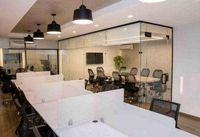 Professional coworking area with rows of white desks and a glass-walled meeting room.