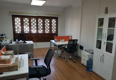 Modern shared office with white desks, orange privacy screens, and wooden flooring.